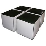 Set of four white leather ottoman cubes with black tops.
