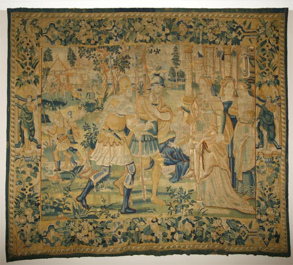 Large 17 century tapestry of soldiers greeting royal ladies; floral border with ancient robed men in niches.