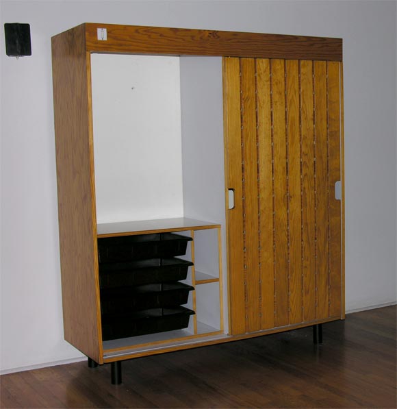 Wardrobe made of pine with a single sliding door, laminate shelves, molded plastic drawers, and an overhead light. Signed 