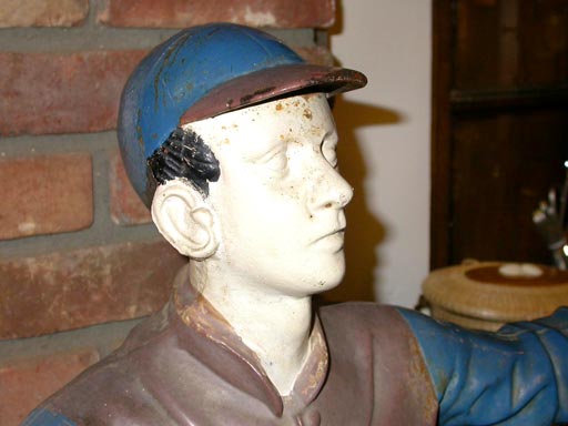 Cast iron lawn jockey.  Painted blue with beige vest white face hands and pants, black boots.