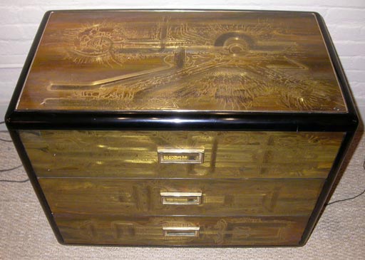 Low chest with rounded ebonized case. Acid etched panels on drawers, top and sides. Hanging brass pulls. Made by Mastercraft.