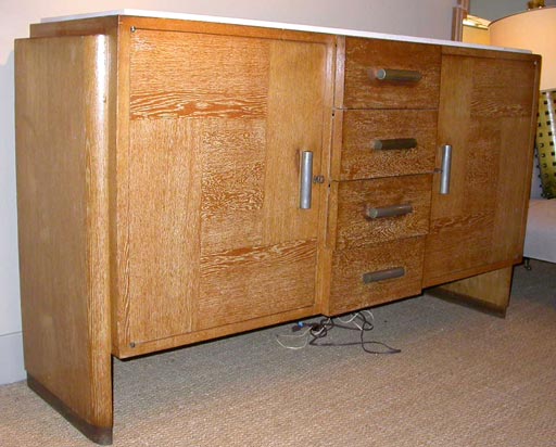 Cerused oak buffet with a limestone top.Two large side doors with interior shelves. Four center drawers.Cylindrical aluminum pulls.