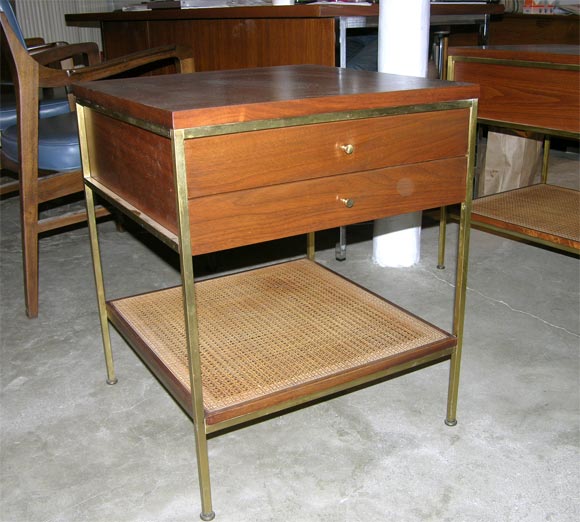 Pair of Paul McCobb bedside tables from the Calvin series.<br />
Brass lages and pulls and a lower cane shelf.