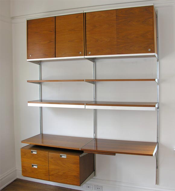 A wonderful example of George Nelson's Comprehensive Storage System (CSS), comprised of four sliding doors, a desk with  pencil case, three storage drawers, five adjustable shelves, and flourescent lighting apparatus, all of which may be positioned
