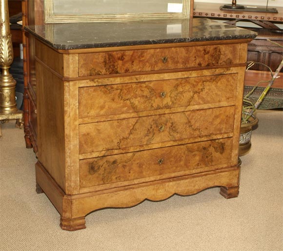 A burl elm and walnut commode with a black marble top made in France during the first half of the 19th century.  Nice warm color with book matched burled veneers on the drawer fronts.