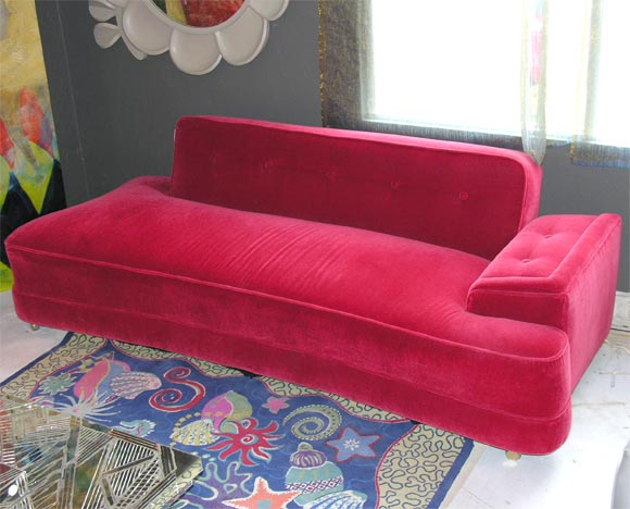 Bone shaped sofa/ daybed in bright raspbery wool mohair
With the backrest that drops down to convert it to a sleeper,
Mounted on brass casters.
 