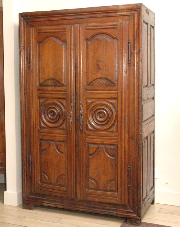 Late 18th century French carved cherrywood armoire. Country armoire with carved panels, roundels, iron hardware, and square feet. Great for storage or as a storage cupboard, comes with lock and key. 