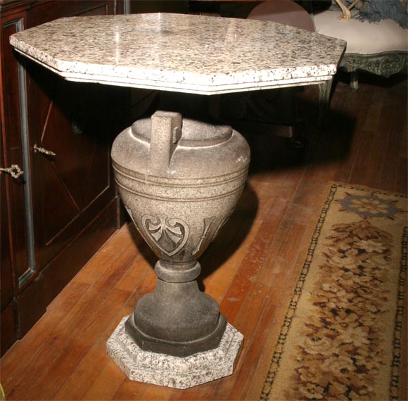 This late 19th century table consisting of two different colors of granite is centred on a dark grey granite urn raised up on a long thin socle. The urn body using as its decorative element a continuous band of anthenium. The urn terminates at the