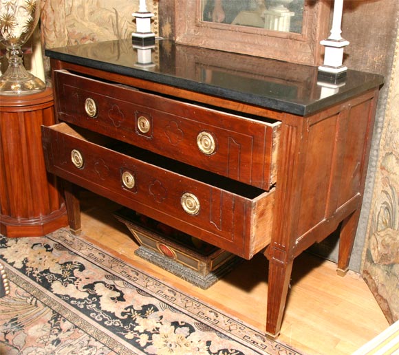 Two-drawer commode with thick black stone top and gilt bronze hardware.