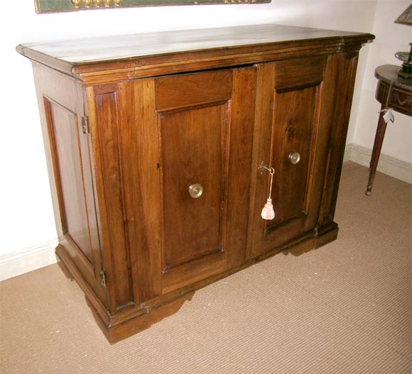 The 18th century Italian walnut two-door credenza has recessed front and side panels. The bronze pulls are original. Inside has one interior shelf.