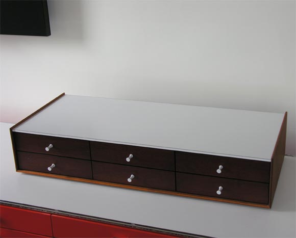 Important example of George Nelson's miniature jewelry chests for Herman Miller.  Six rosewood drawers with porcelain pulls, one with interior dividers; walnut frame and white laminate top.  Just lovely.