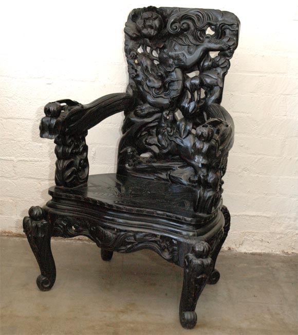 This is a bold and impressive carved arm chair. The ebonized wood, which is pierced by carving in places, has bone inlaid as the dog eyes. The overall effect is a very substancial arm chair showing pleasing details on: the back, legs, seat and arms.