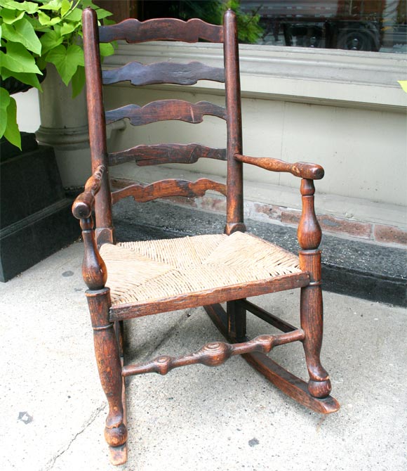 Very charming English childs rocking chair with rush seat.  Very nice old finish with good color and patination. Rush seat in very good condition.