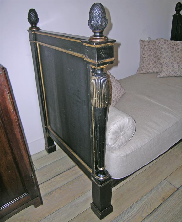 An Empire ebonized and gilt day bed with linen upholstery and two cushions
