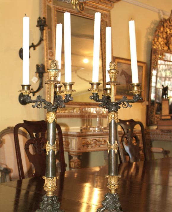 A PAIR OF CHARLES X PATINATED AND GILT DORE 3 LIGHT CANDLEABRA. EACH ACANTHUS LEAF BRANCH SURROUNDING A CENTER BRONZE TORCH FINIAL. AN INSWEPT STEPPED BASE SUPPORTING THE TRIPOD OF WINGED LIONS.