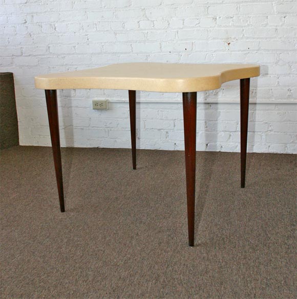 Free formed cork top table with stained mahogany legs designed by Paul Frankl. The photos posted here are not quite accurate in color. The top is a rich cream color and the legs are darker. This table has been restored to match the original color