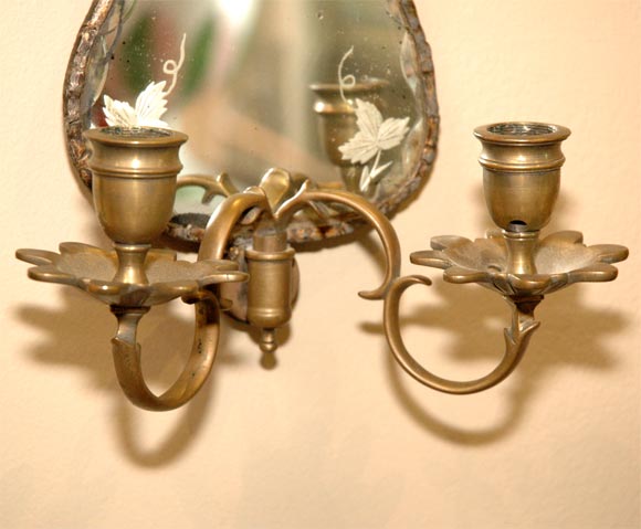 Dutch, pewter-bound pair of engraved, mirror-back sconces with brass arms.  Engraved vignette features charming, naive depiction of putti and a vase with unusual leaf and wheat motif.  The outer edge of the glazing is scalloped.