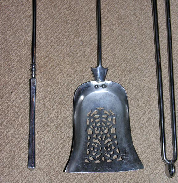 An impressive set of English steel fire tools, the octagonal faceted handles with knob finials, the shaped shovel with pierced lacework. Very fine quality and good weight.