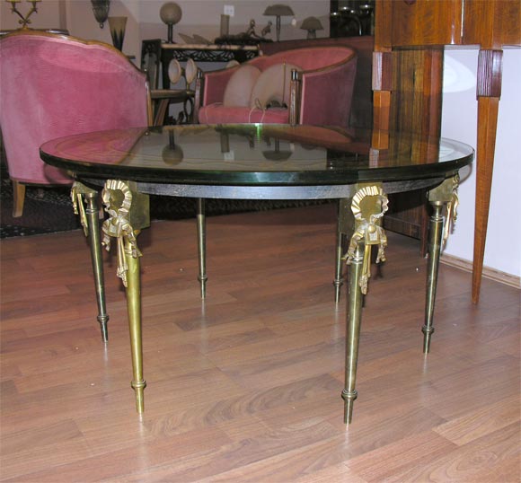 A low cocktail table by Maison Jansen, from circa 1940s with a mirrored top on six bronze legs accented with stylized ribbon decoration.