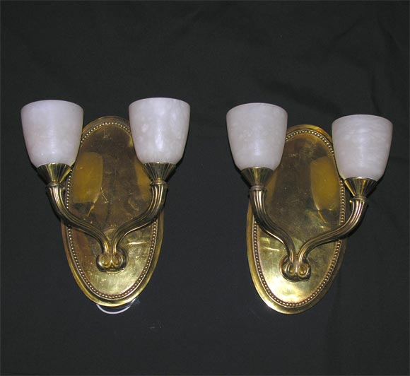 A pair of modern deco-style wall sconces, two-armed, with alabaster shades.