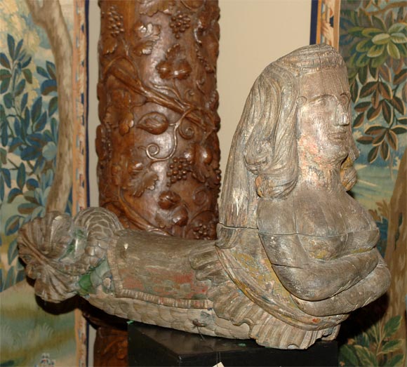 The recumbent long haired and full-breasted creature with folded arms, her caparisoned scaly body terminating in a coiled fish tail; traces of old red, green and ocher paint. Note: this is an ornament from the side of a private barge or yacht.
