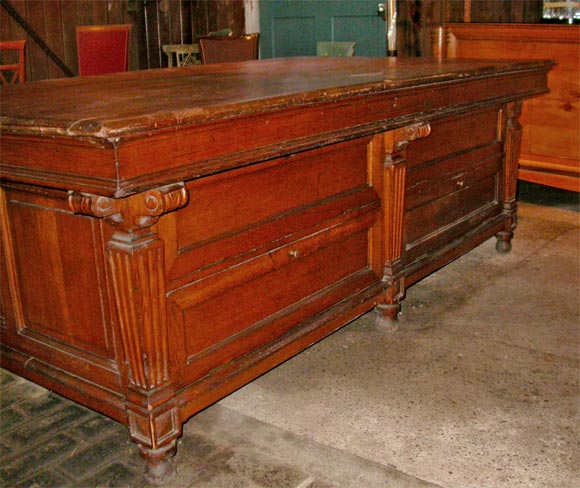 19th century oak draper's counter. Finished on four sides with the long sides consisting of four hinged door shelves each. There are six fluted pilasters each ending in a small bun foot.