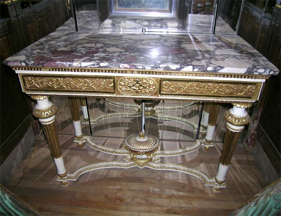 This Louis XVI console table is made from carved wood that has been gessoed then painted and gilded in several colors creating a rich play of color. The deep apron is fully covered in carved and applied wood decorative floral detailing. This is