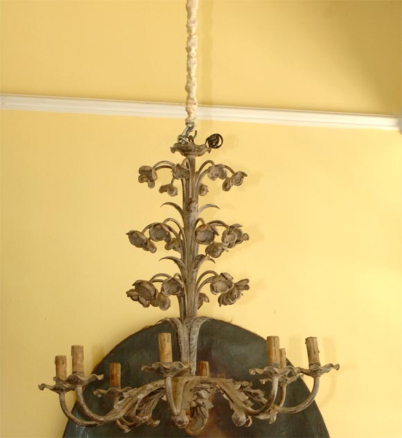 A CAST IRON AND PAINTED CHANDELIER WITH ABUNDANT FLOWERHEADS AND ACANTHUS LEAVES THROUGHOUT.