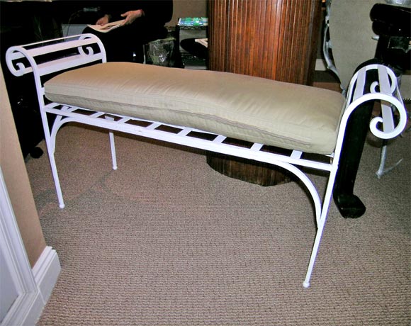 Painted iron bench with slatted scroll arms.  Interlaced iron forms a lattice-like seat.  Legs sit on small ball feet.