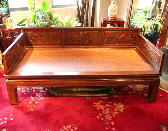 19th century Chinese opium bed with carved botanical and animal motifs, and woven rattan seat.  The walnut wood has a rich golden hue.