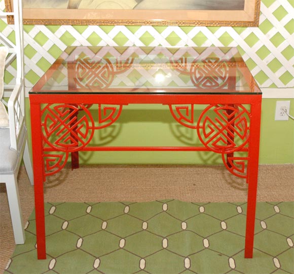 Red garden table with chinoiserie detail and glass top.