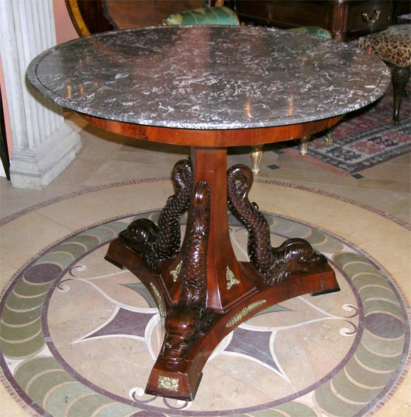 Fine French Empire marble-top bronze mounted center table with beautifully carved Dolphins on Tripartite Base. The dish top marble is fossilized and the pedestal bronze mounted base mahogany.