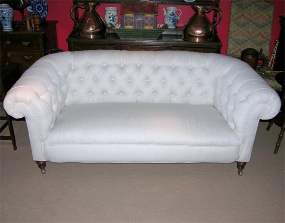 English 19th c. country-house button-back chesterfield sofa having a deep seat with rolled arms on original turned legs with original brass castors.  Very comfortable yet tailored.