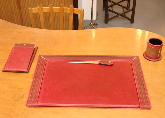 Unbelievably stylish desk set by Gucci.  The note pad cover, pencil holder, desk blotter and letter opener are all covered in a vintage red leather with a gold Gucci symbol on each piece and framed in brown leather.  Who wouldn't want a desk