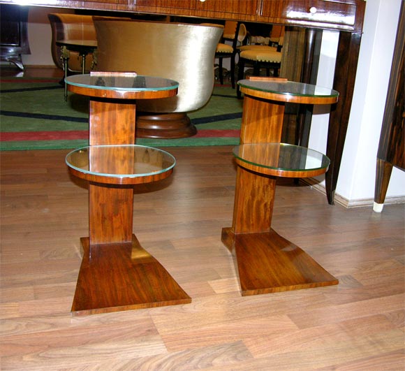 A pair of French Art Deco side tables stamped Jules Leleu, in mahogany wood and featuring two circular mirrored shelves.