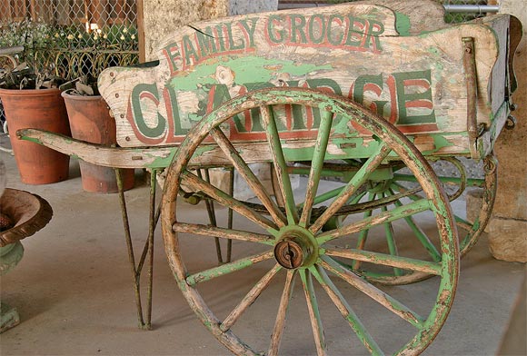 English wooden grocery cart with Claridge Family Grocer painted on each side panel.