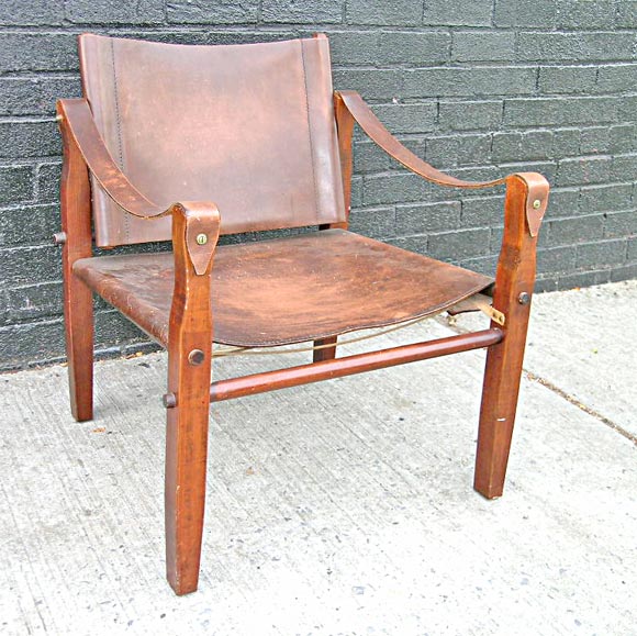 Old and orignal wood and patina'd leather Safari chair.  The chair's simple design allowed explorers a comfortable, elegant, easily transportable chair. The wonderful distress on the thick saddle leather seat and armrests suggest an active life