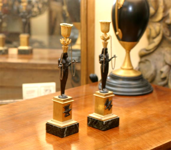 A pair of gilt and patinated bronze figural candlesticks on marble plinths.