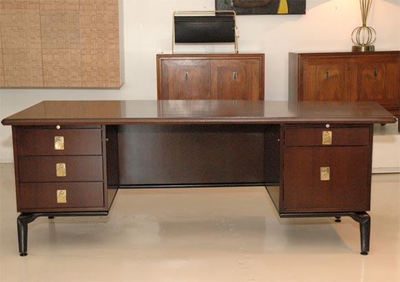 Large asymmetrical executive desk in a dark walnut finish by Monteverdi-Young with wonderful details.  Ebony inlay to the perimeter of top, and ebonized base with decorative details.  Five drawers including one file drawer. Two pull-out writing