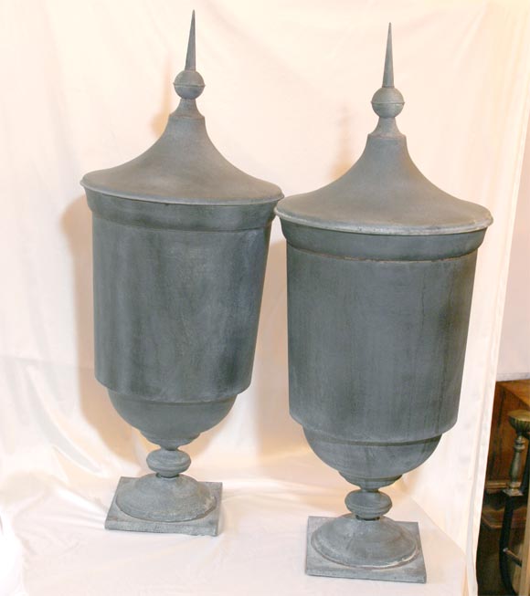 A PAIR OF LIDDED URNS, IN A SMOOTH MATTE GREY, DISTRESSED FINISH