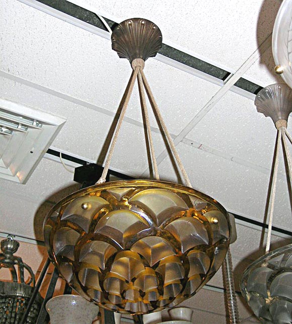 Lalique chandelier, in amber glass molded in a honey-comb pattern, hanging on four silken electrified cords, with original glass canopy. Additional chandeliers for this design are available.
