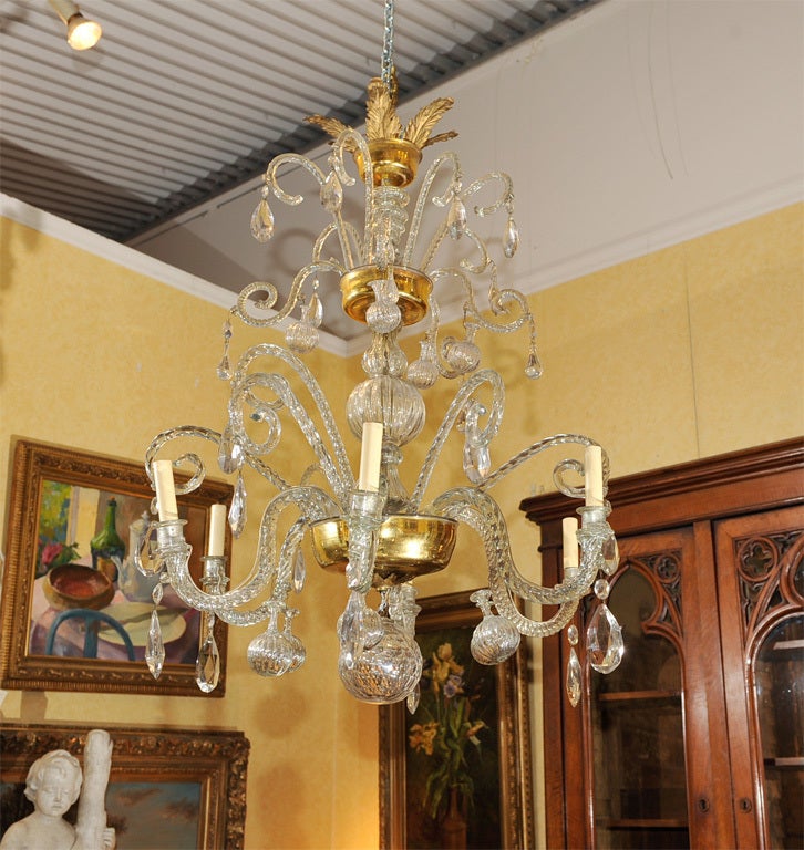 A LEAF CAST CORONA ATOP THE UPPER CIRCULAR TIER FITTED WITH 12 GLASS SCROLLS AND SMALL VASES , FACETED PRISMS AND DROPS,ALL HAND BLOWN.THE LOWER TIER, WITH 8 CANDLE ARMS, FITTED FOR ELECTRICITY, ALTERNATING WITH SCROLLS HUNG WITH PENDANTS AND LARGER