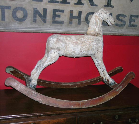 A sculptural, hand-carved 19th century Folk Art rocking horse in its original chalk white paint on carved and auburn painted rockers. This horse possesses an alert and lively stance. He is a fine piece of Folk Art for a country house.