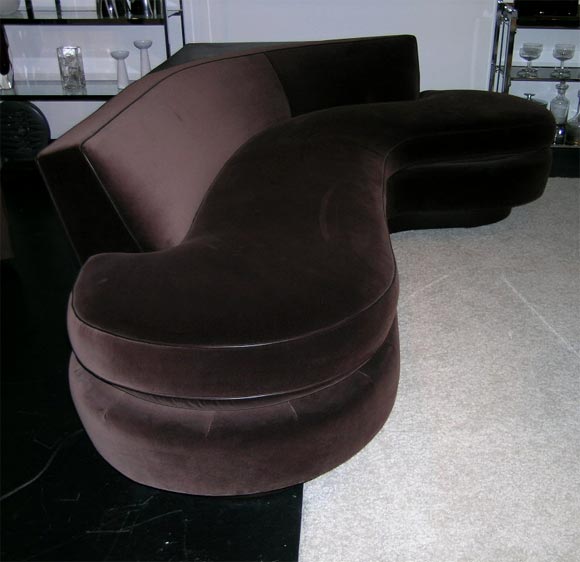 L shaped singualr cushion upholstered in chocolate brown velvet and leather piping on a brown leather base