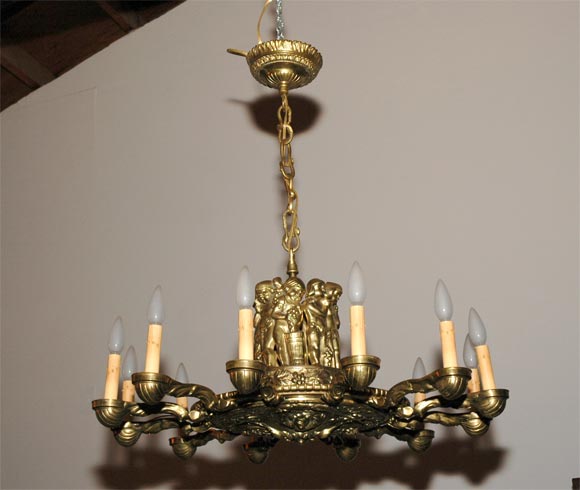 Made for the wine and champagne atmosphere, this chandelier is big, bright and makes a bold statement. The central detail (above) has three wine makers at their task atop a band of grapes and leaves. Twelve golden cups hold the lamps at the end of