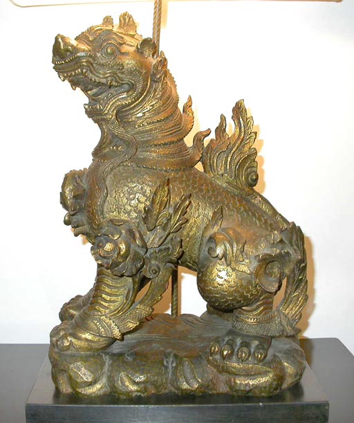 A pair of hand carved gilt-wood with gold leaf Foo dog lamps,
nestled into a grooved base which fits the form perfectly. All brass fittings are custom antiqued brass with a twisted rod which holds a double socket.
An exceptional and highly