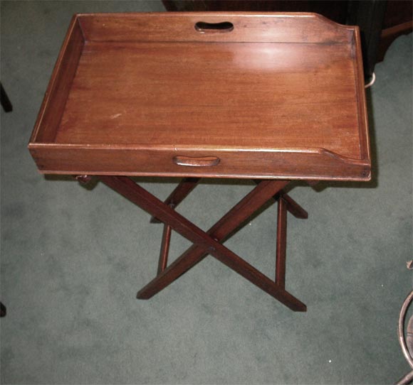 An antique mahogany butler's tray, with serving handles, on a folding stand. Serving height.
