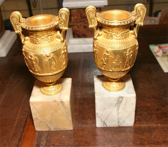 A pair of gilt bronze Grand Tour urns mounted on marble bases.