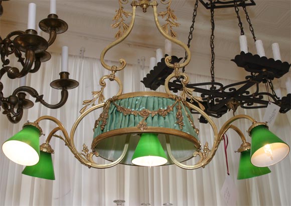 A WIDE AND SHALLOW BRONZE CHANDELIER WITH GREEN SHADES. THE LENGTH OF THE DROP CAN BE ALTERED, AND MADE SHORTER.