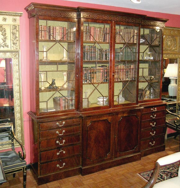 Georgian mahogany breakfront bookcase. Two pair of geometrically glazed doors, base with two mahognay panel doors and two sets of drawers. ( 5 drawers each ) Crown decorated with fretwork relief.